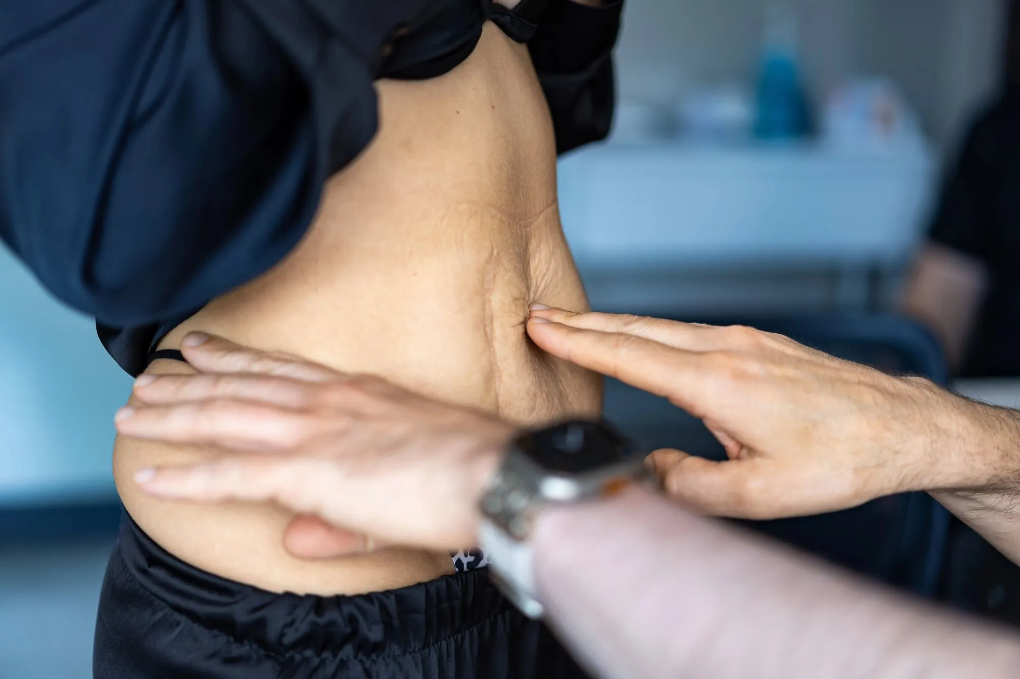 Foto-Brief: dokumentarisch, eine Frau einige Wochen nach der Geburt liegt entspannt auf einer Matte zu Hause, eine Hand ruhig auf dem Bauch, Tageslicht — warm, alltagsnah, nicht klinisch, kein Übungs-Posing. Keyword: Rektusdiastase nach der Geburt.